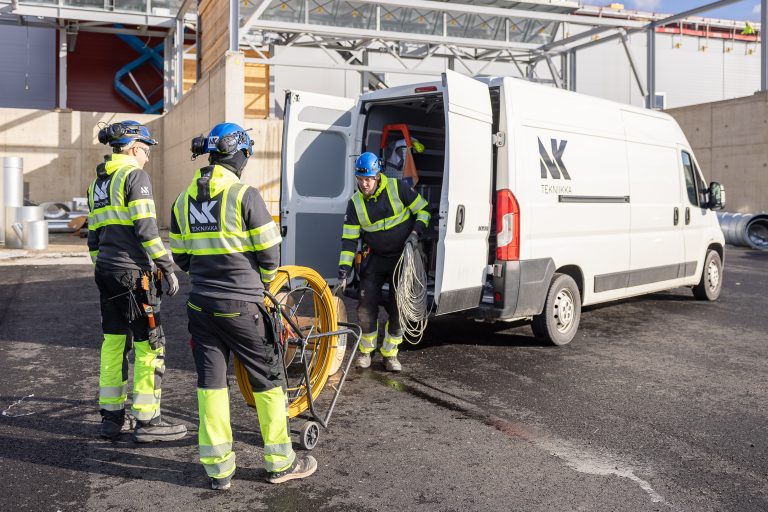 NK Tekniikan sähköasentajat purkavat kaapelikelaa pakettiautosta työmaalla